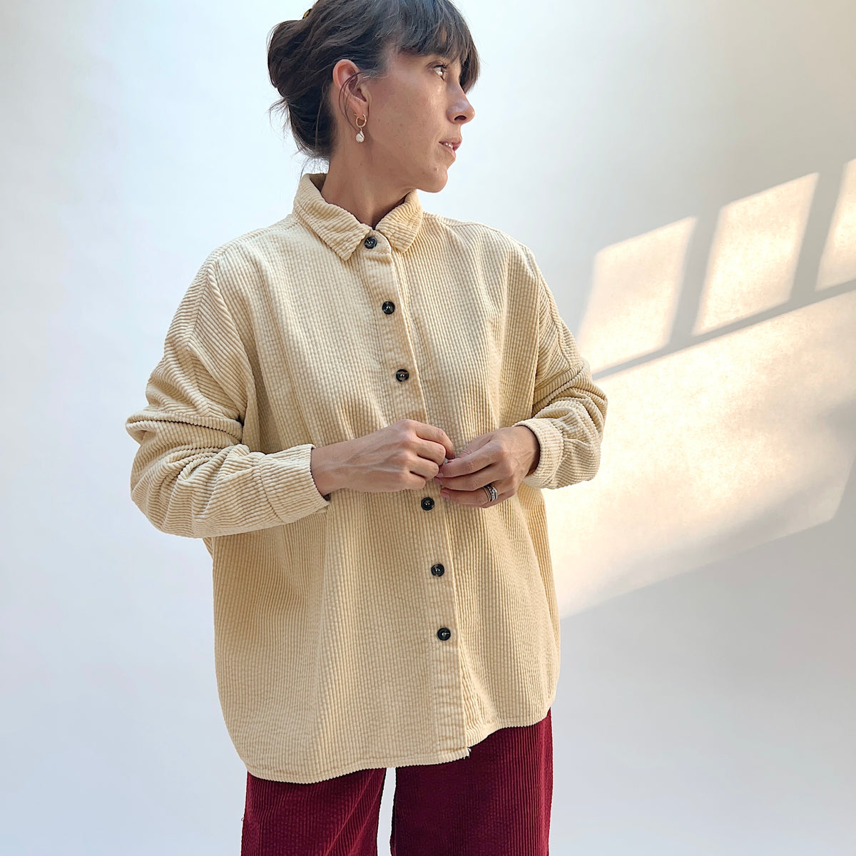 Front view of the Lux Corduroy Oversized Shirt in Glow on a model, showing the collar, button front, and vertical corduroy texture.
