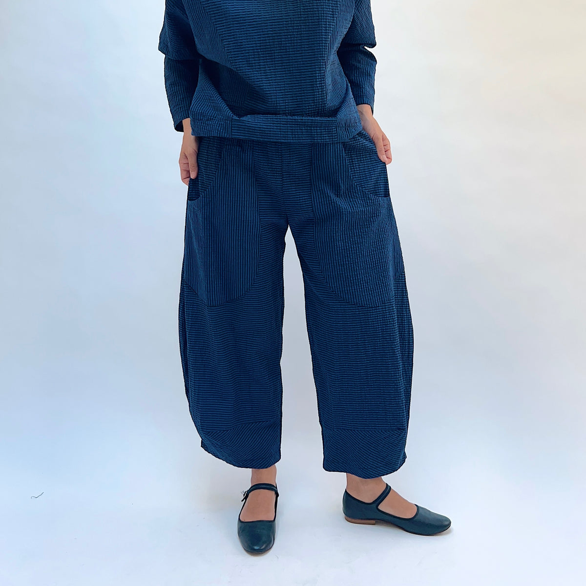 Niche Izzie Pant in Blue Seersucker Stripe, front view showing the full wide-leg silhouette and front pockets in teal and black seersucker stripe
