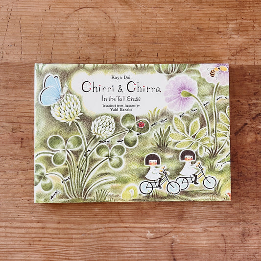 Cover of 'Chirri & Chirra: In the Tall Grass' featuring illustrations of two children on bicycles, surrounded by grass, flowers, and a butterfly.