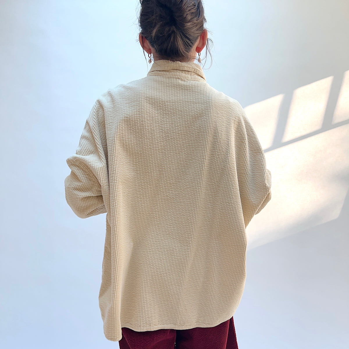 Back view of the Lux Corduroy Oversized Shirt in Glow on a model, showing the vertical corduroy texture and curved hem.
