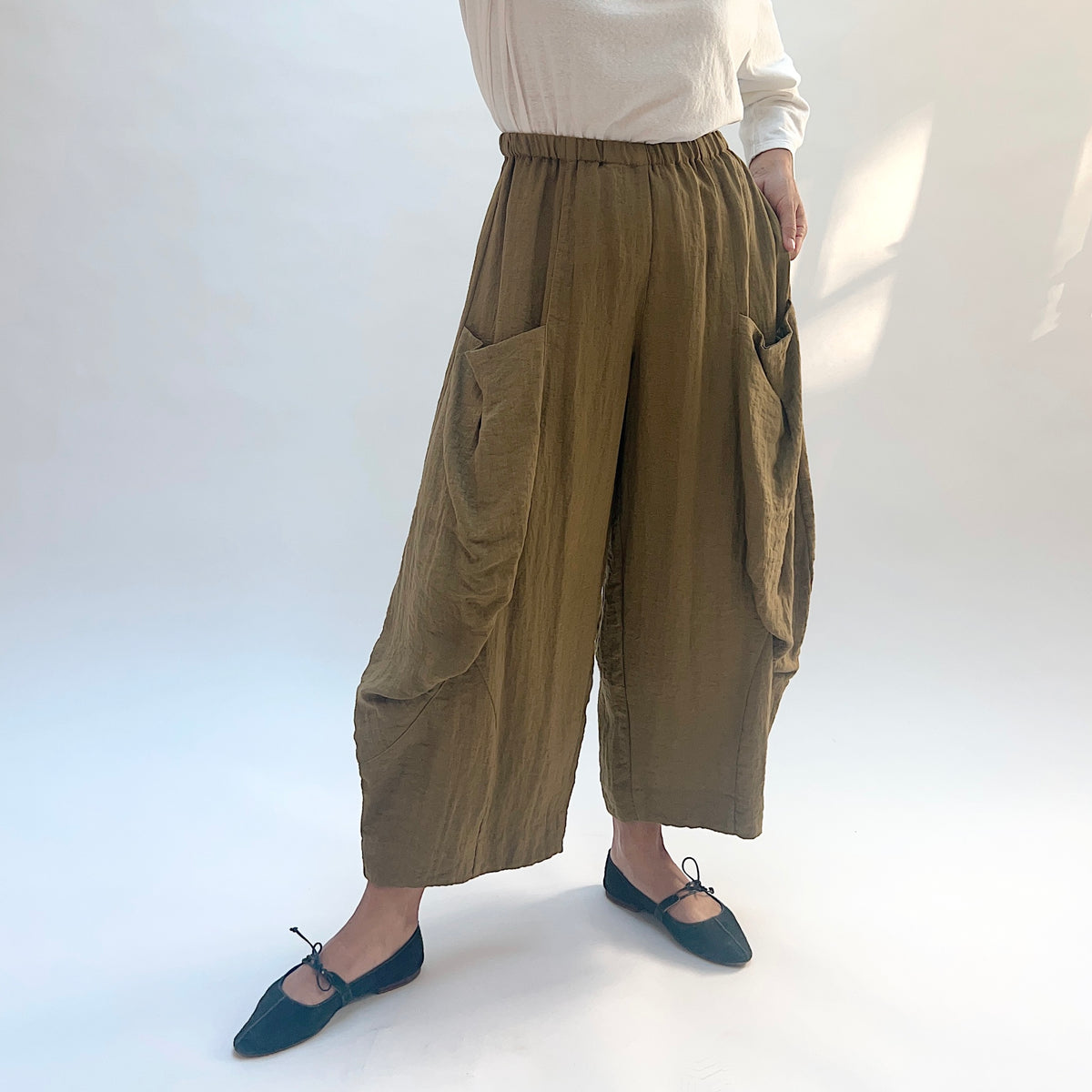 Eleven Stitch Double Pocket Crinkle Travel Pant in Olive, front view showing the gathered waistband, crinkled fabric, and large side pockets.
