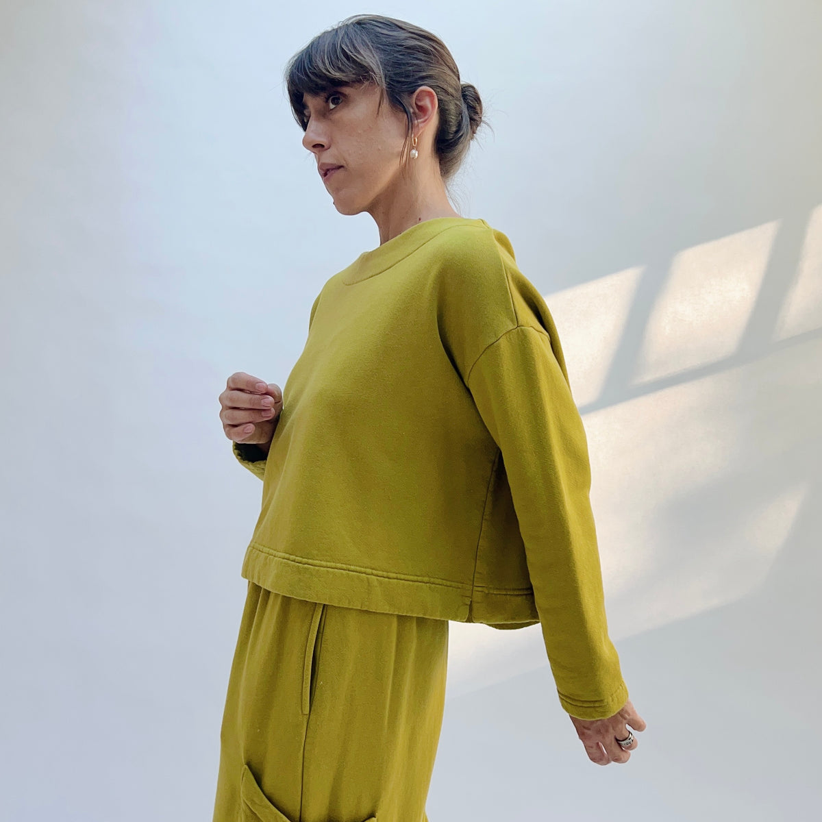 Side view of Button Back Fleece Pullover in Chartreuse, showing the long sleeves and short, boxy shape.
