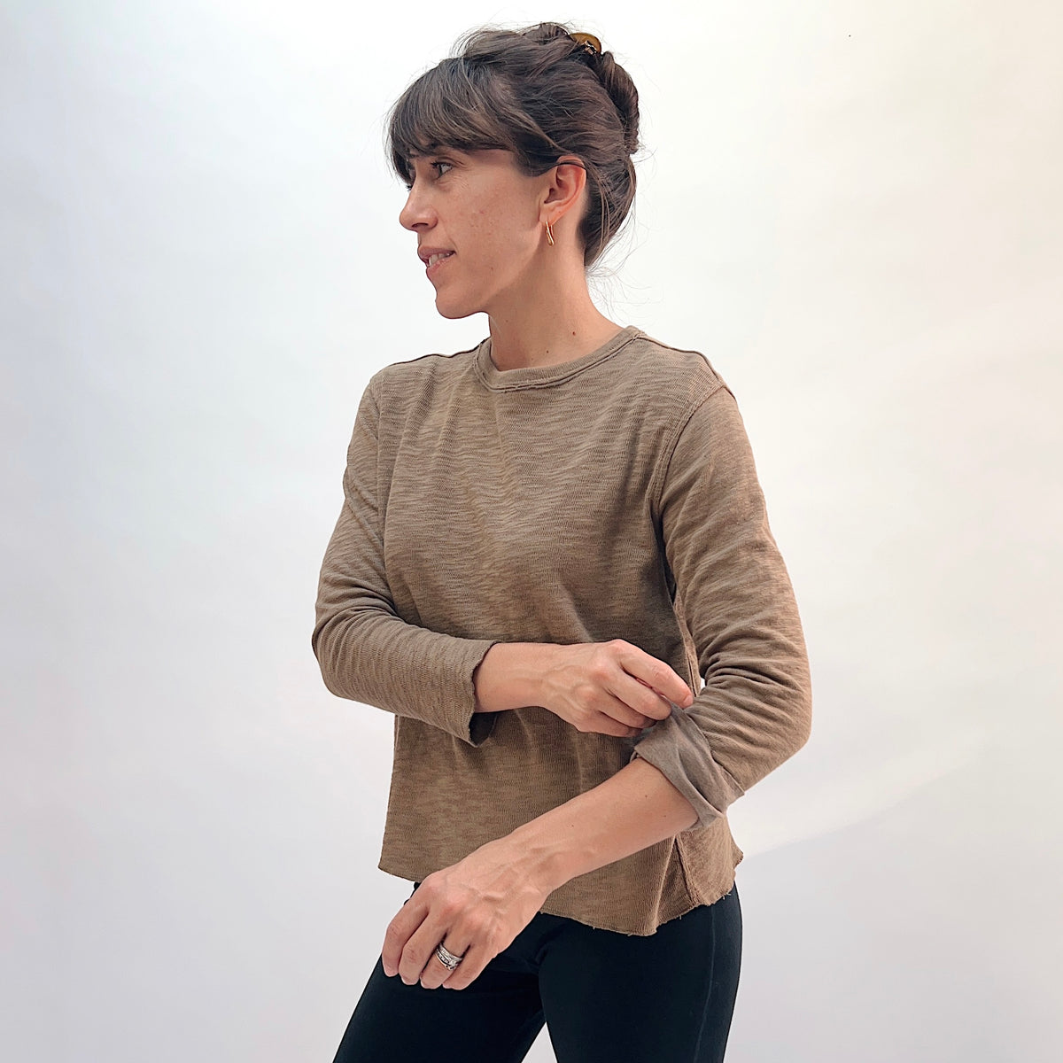 North Star Base Double Cotton Tee in Winter Olive, side view showing the raw-edge finish at the bottom hem and relaxed silhouette in warm olive
