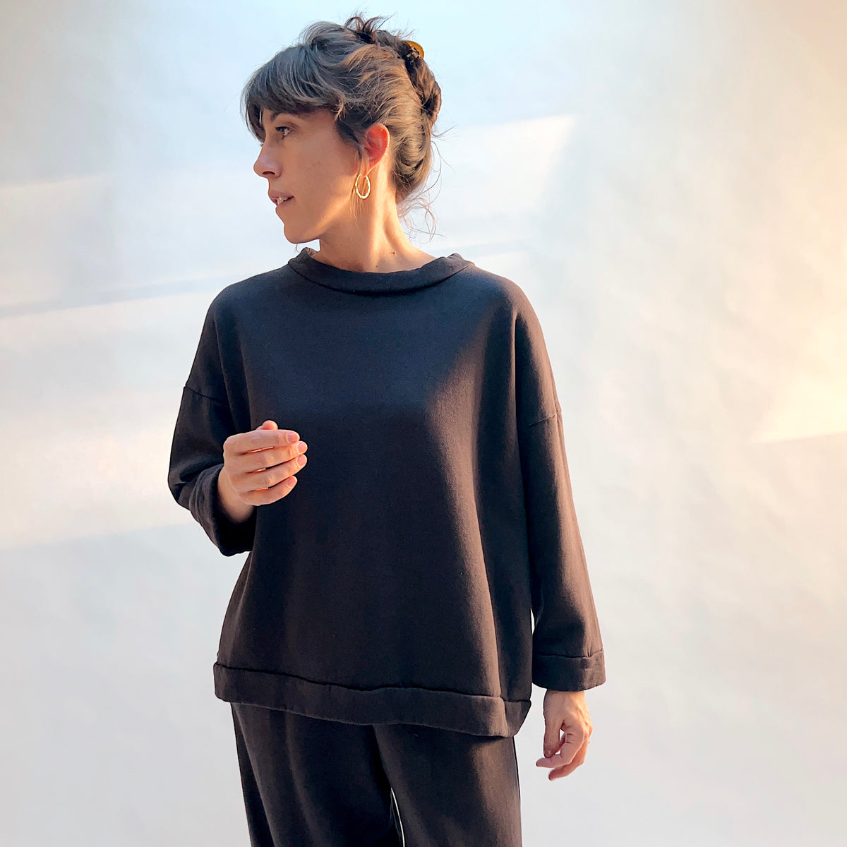Front view of Bryn Walker Alden Fleece Sweatshirt in Fig on a model, showing the draped neckline, dropped shoulders, and banded hem.

