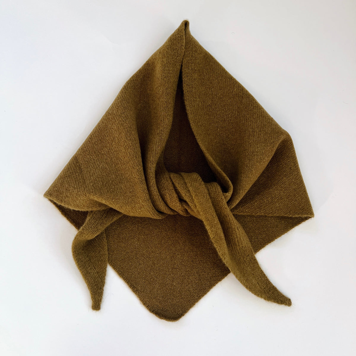 Flat lay view of the Winter Olive merino wool triangle scarf arranged with a loose knot and pointed ends.
