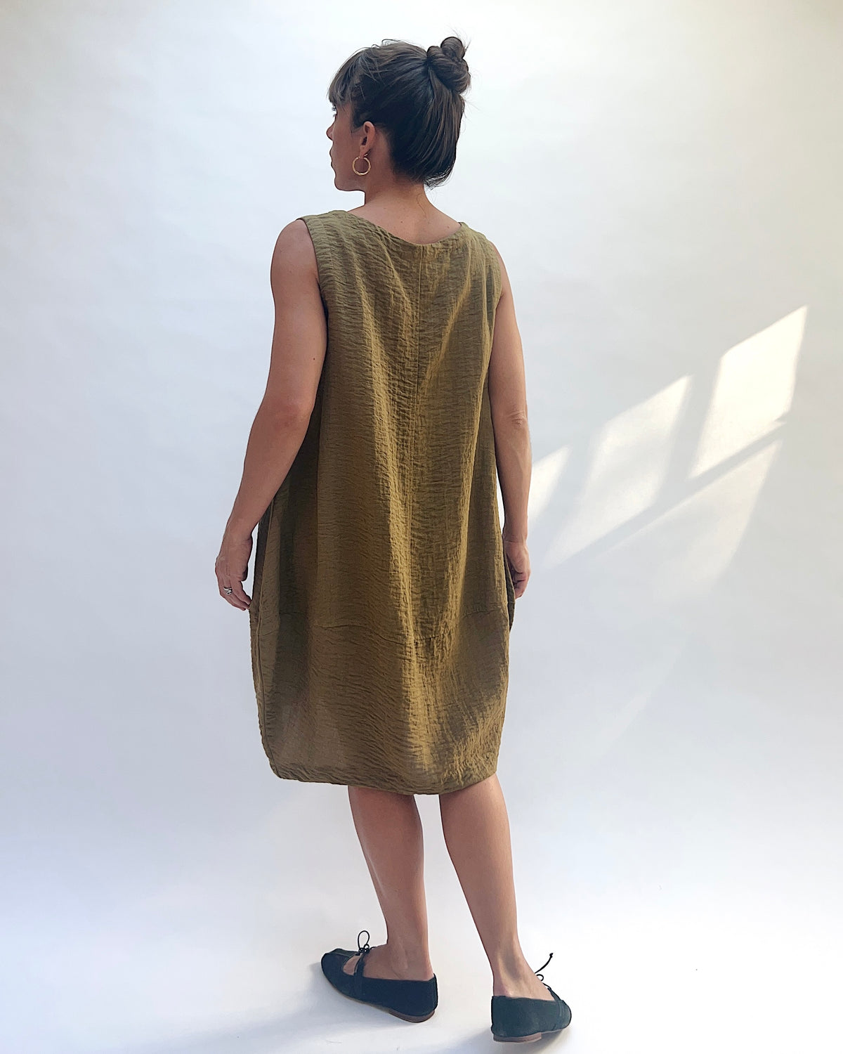 Eleven Stitch Travel Bubble Dress in Teak, back view showing the center seam and rounded hem.
