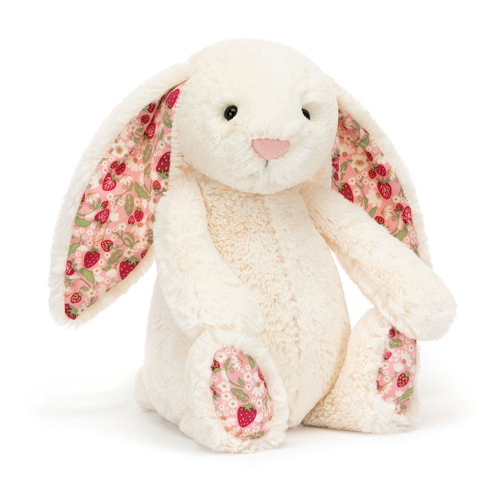 Jellycat Blossom Cream Bunny 'Berry' Original — a soft cream plush bunny seated upright with long floppy ears lined in a pink strawberry and floral print fabric, a pink embroidered nose, black hard eyes, and matching strawberry print paw pads, on a white background