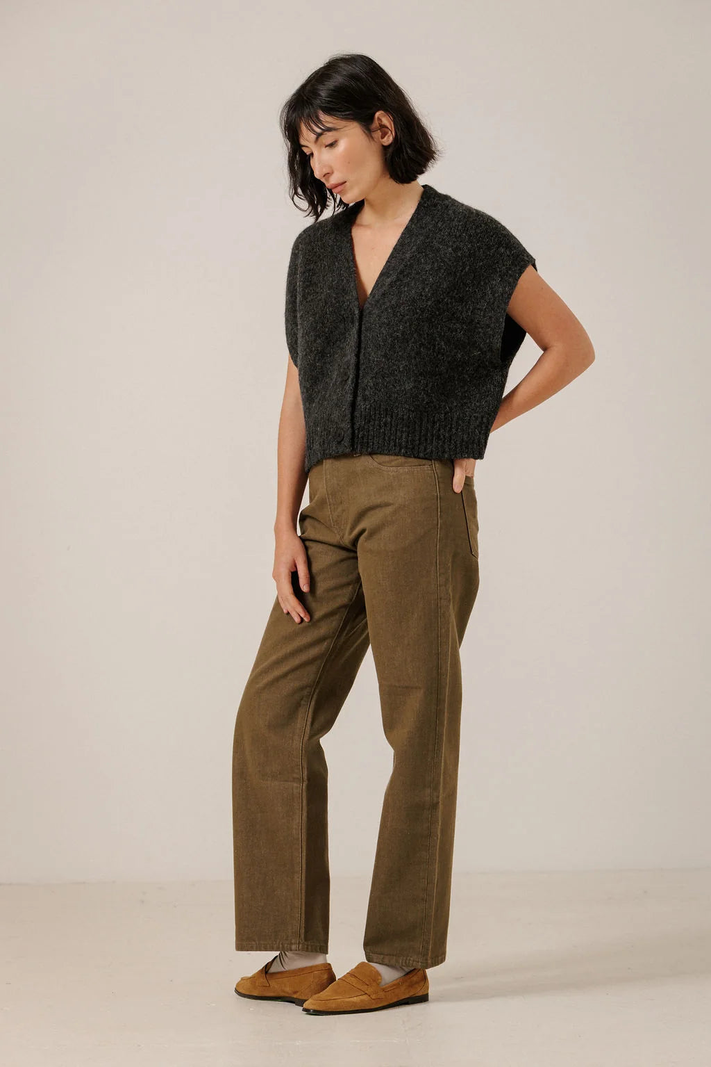 Full-length angled view of a model wearing the Basalt button-down vest with brown trousers.
