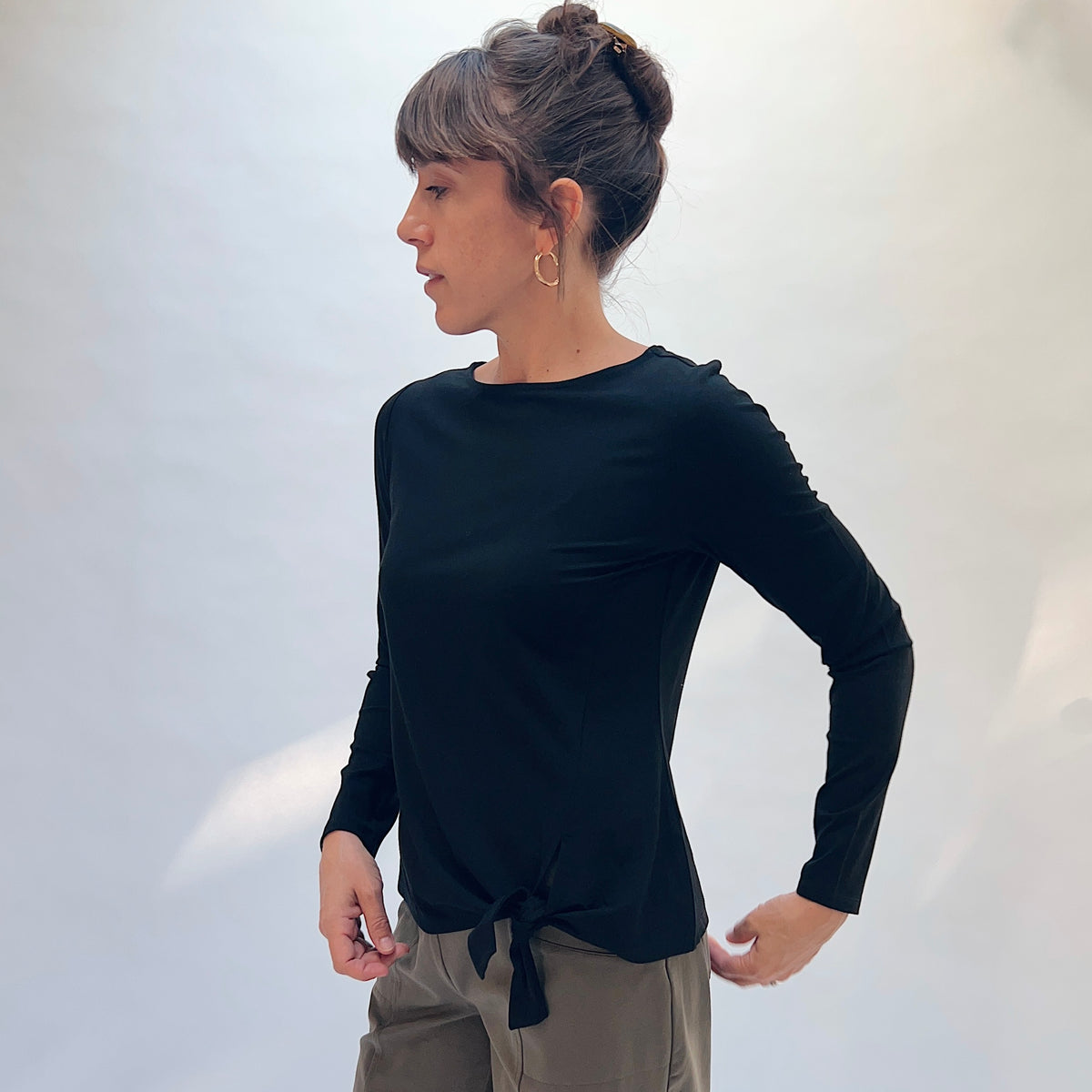 Habitat Core Travel Tie Front Top in Black, front side view showing the tie-front hem detail and long sleeves
