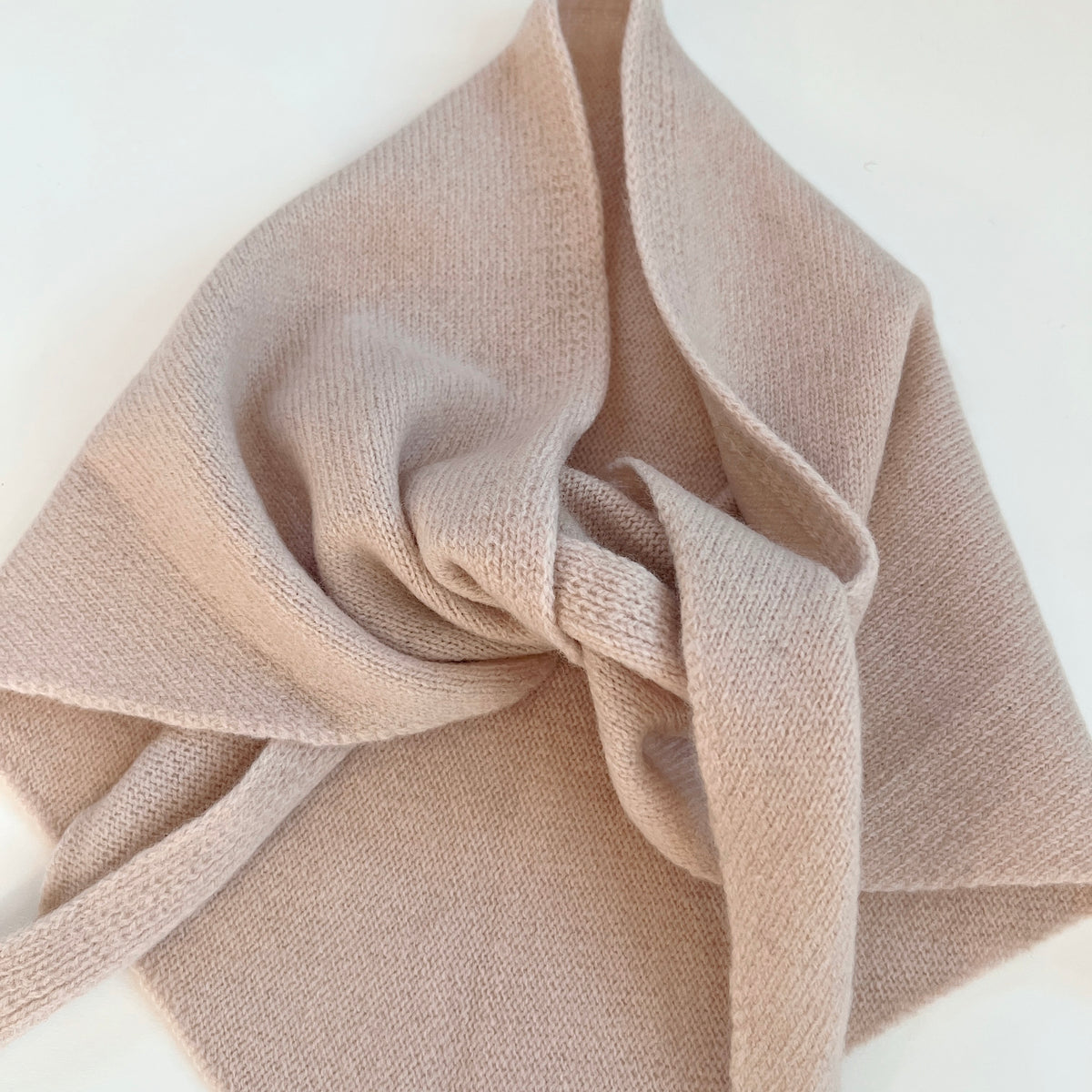 Close-up of the Cream merino wool scarf showing its knit texture, loose knot and overlapping folds.
