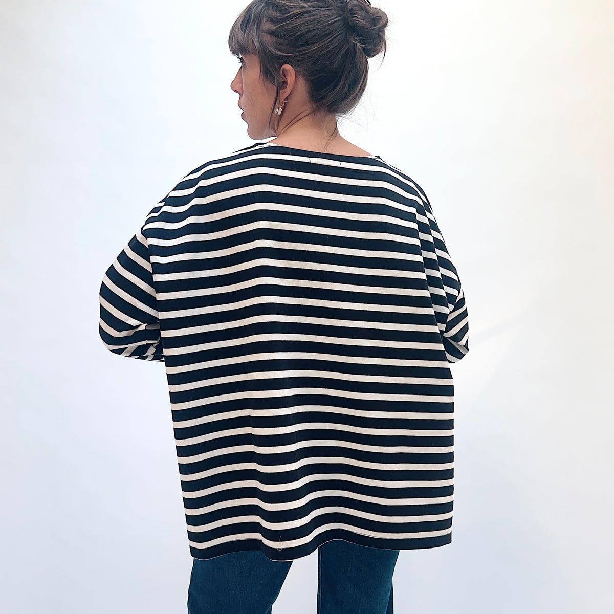 Back view of the black and natural striped knit pullover, showing horizontal stripes and dropped shoulders.
