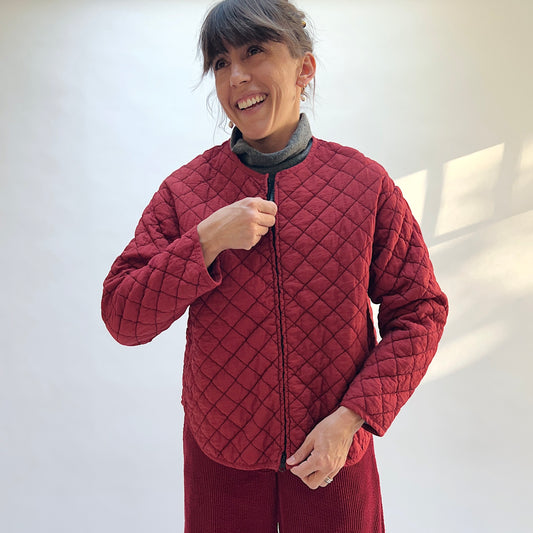 Model wearing the Cut Loose Quilted Bomber Jacket in Maraschino, holding the front zipper and showing the diamond quilting.
