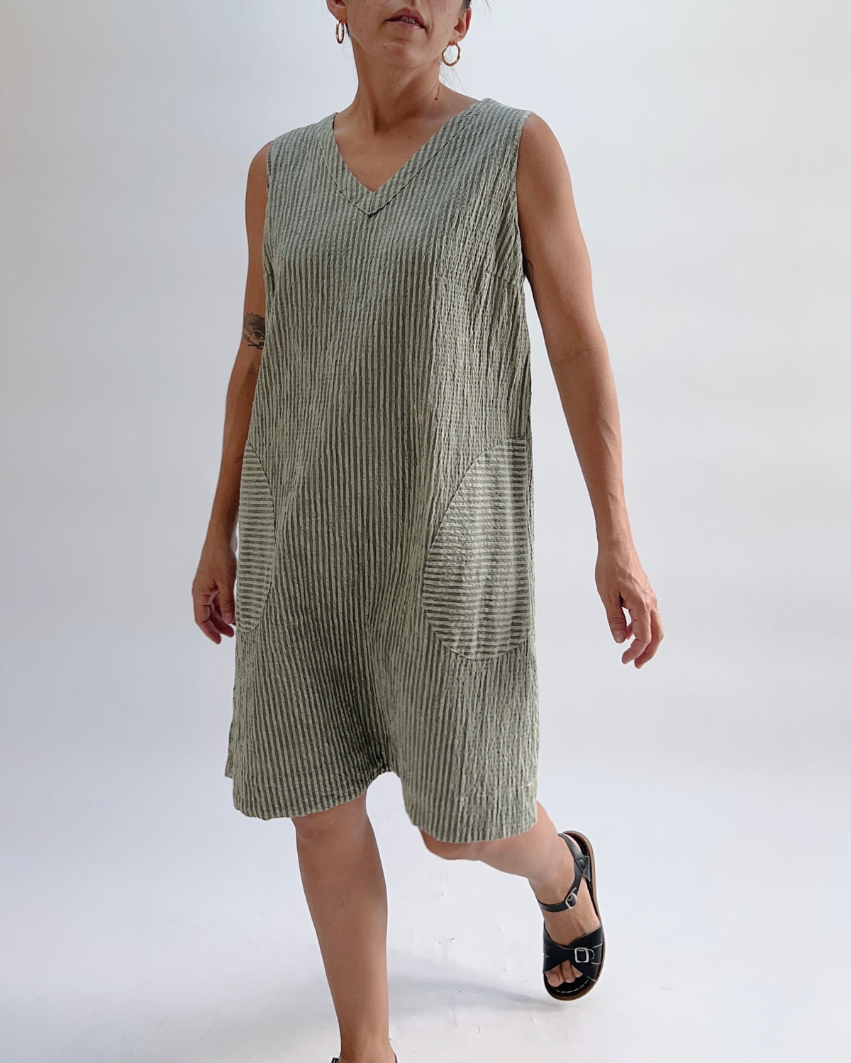 Cut Loose V-Neck Shift Dress in Balsam Green Stripe, three-quarter front view on model in motion, showing relaxed shift silhouette and patch pocket detail, worn with black sandals
