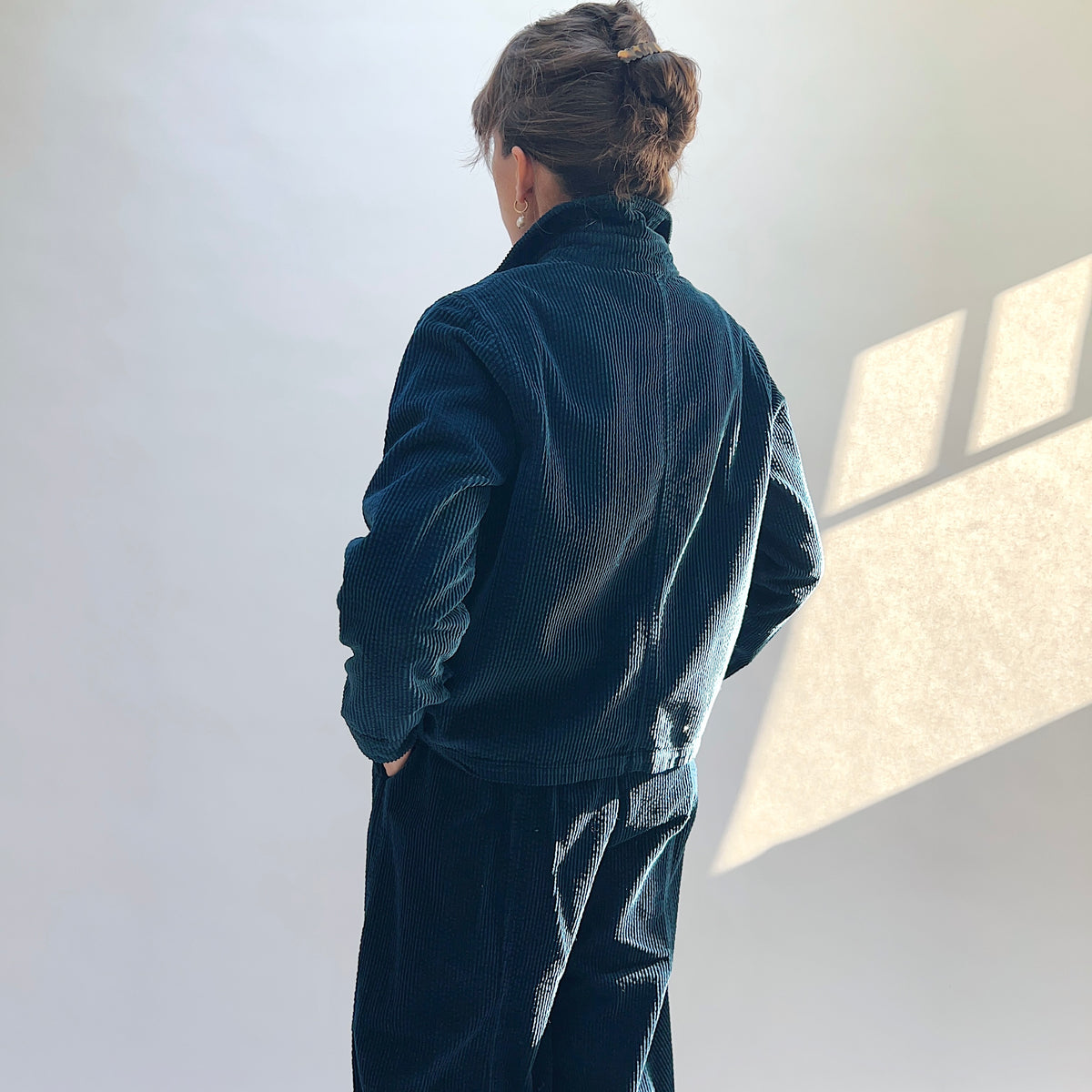 Back view of the Lux Corduroy Cropped Jacket in Etan on a model, showing the vertical corduroy texture and center-back seam.

