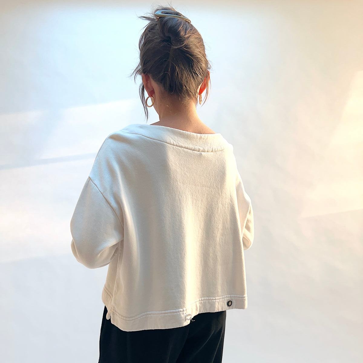 Back view of Button Back Fleece Pullover in Cream, showing the wide neckline and button detail at the lower hem.
