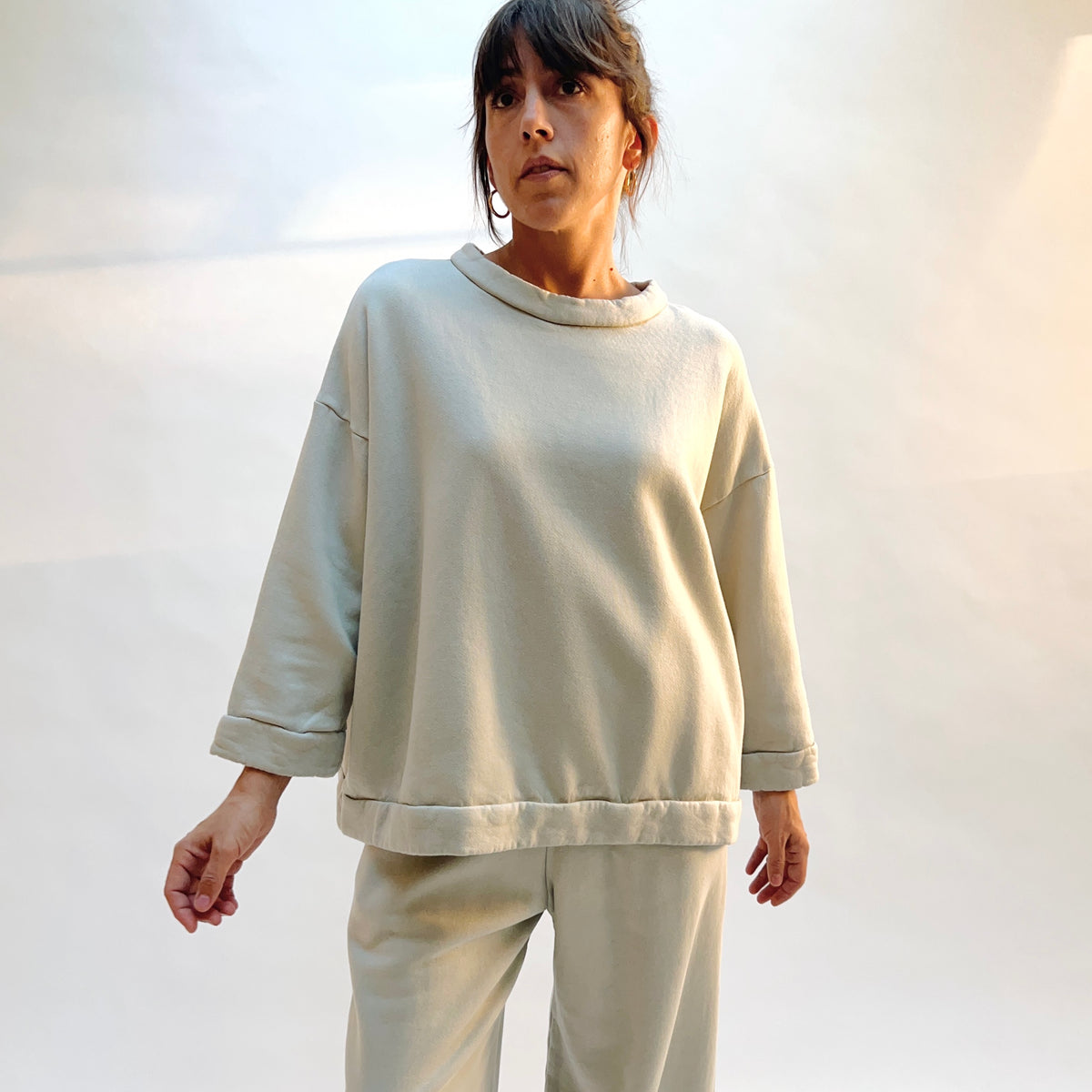 Model wearing Alden Fleece Sweatshirt in Orlaya, showing the loose drape, folded cuffs, and banded hem.
