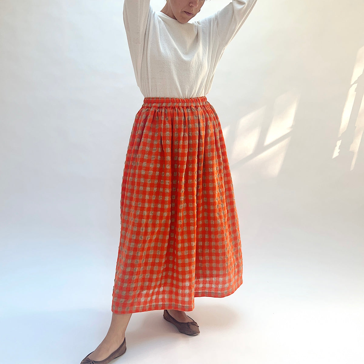 Ichi Antiquités Gingham Wool Check Skirt in Beige & Orange, angled front view with model's arms raised.
