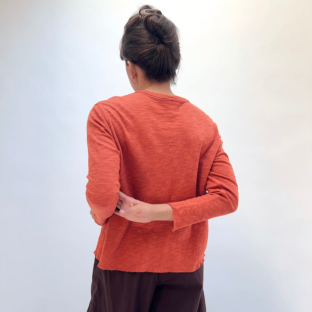 North Star Base Double Cotton Tee in Rusty, back view showing the raw-edge neckline and straight hem in rusty orange
