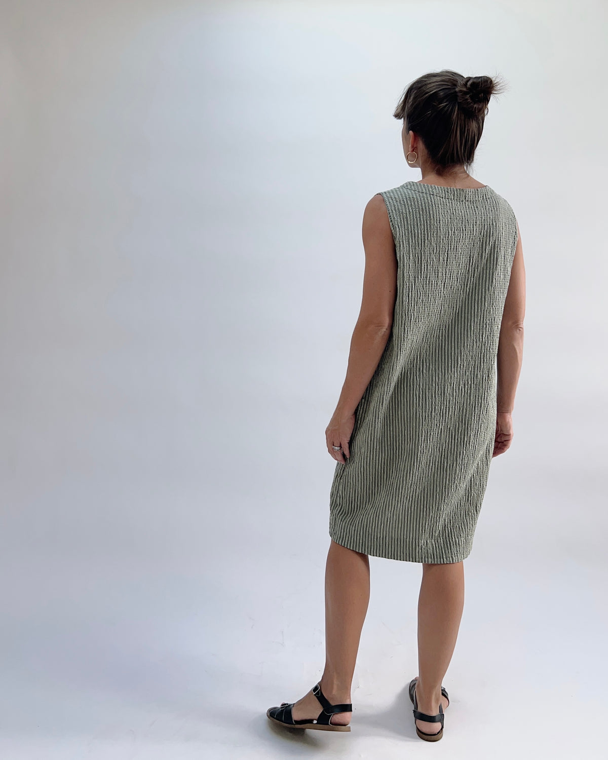 Cut Loose V-Neck Shift Dress in Balsam Green Stripe, back view on model, showing clean back yoke and relaxed shift silhouette, worn with black sandals
