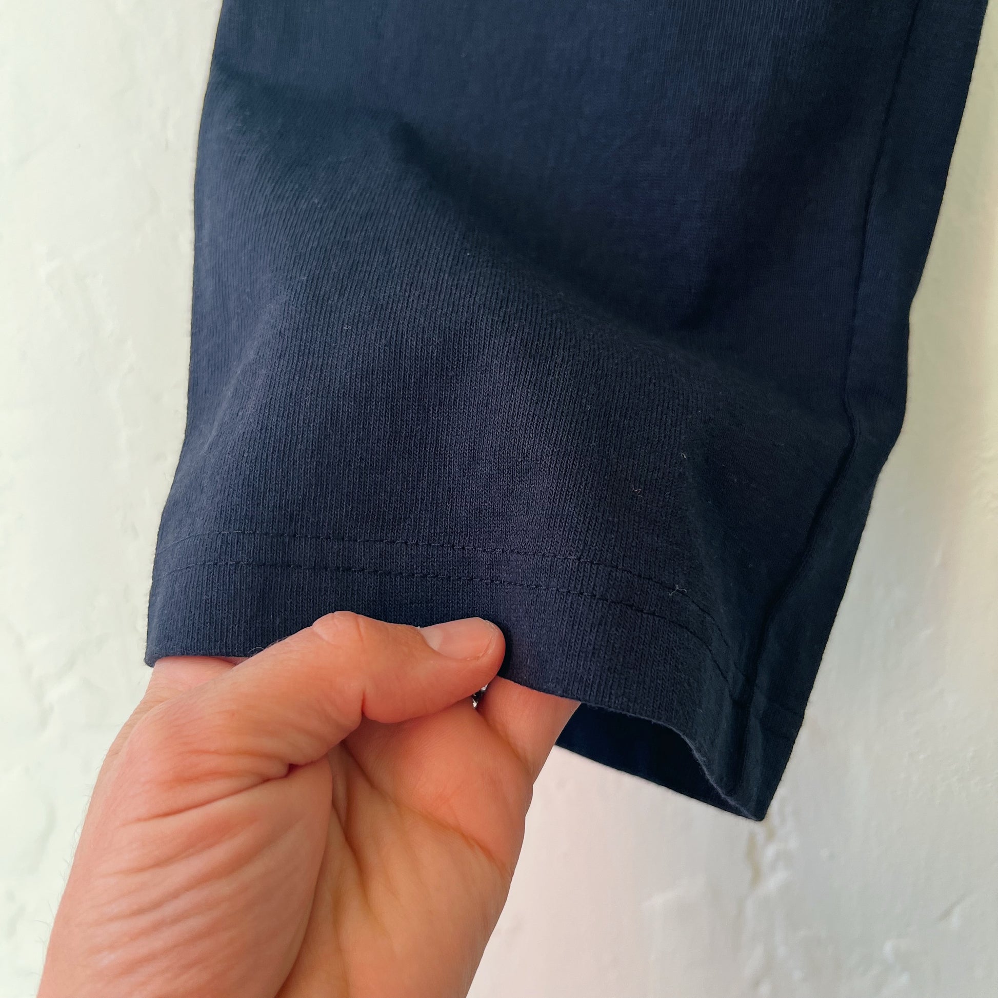 A hand holding close up pant leg of black cotton pants.