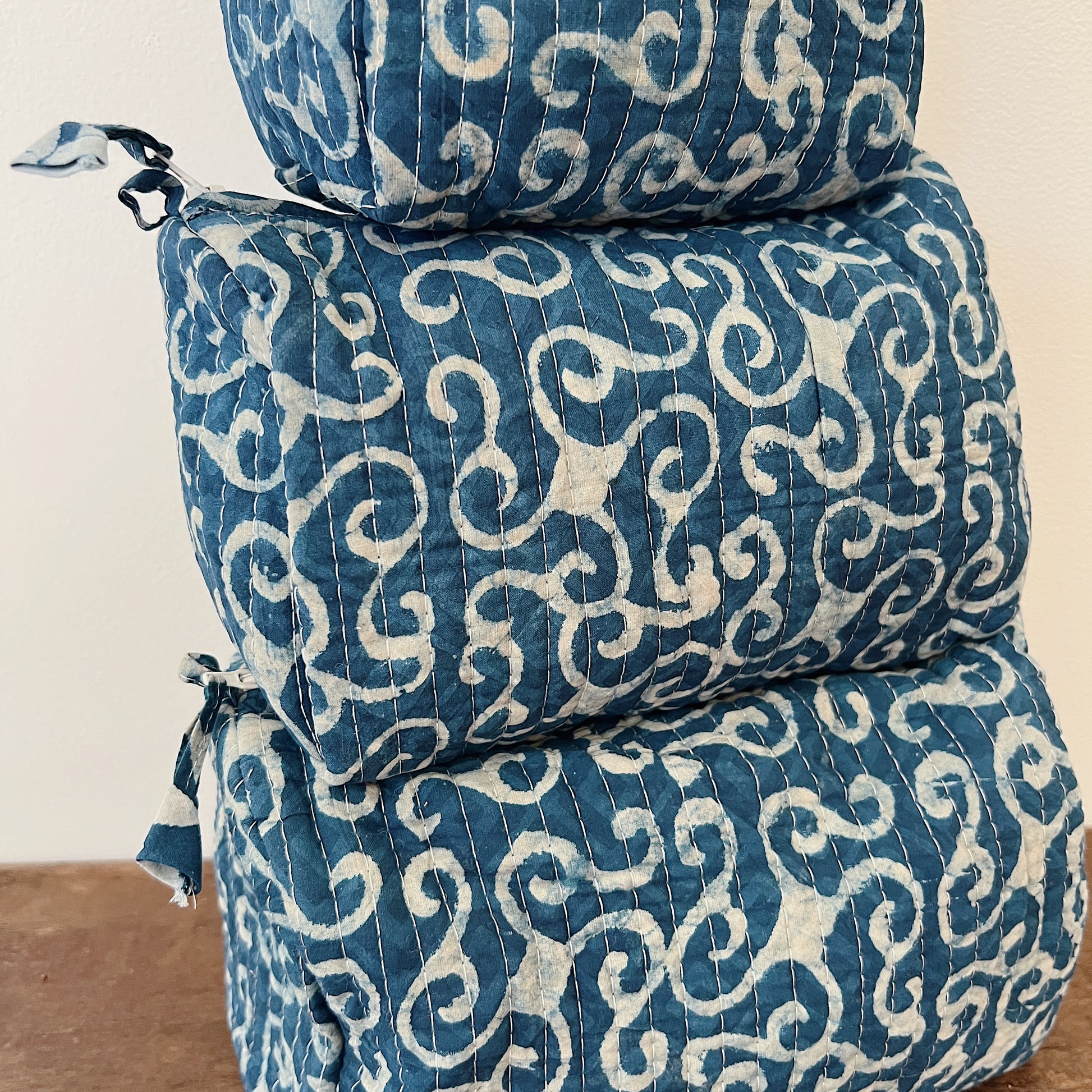 Close-up of the Toiletry Bag in Demeter Blockprint showing the deep indigo quilted cotton with white scrollwork block-print motifs and vertical quilting stitches
