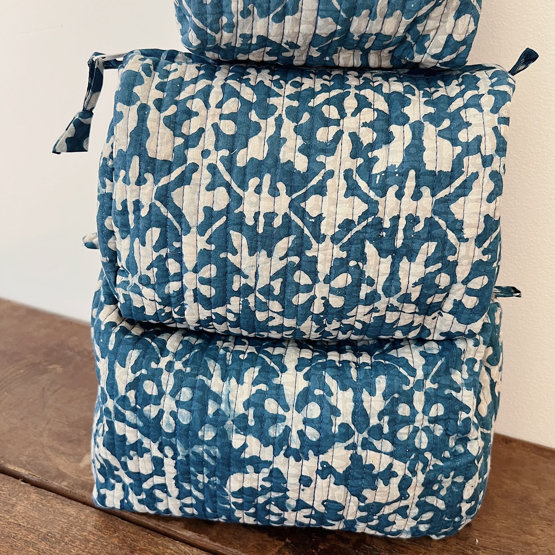 Close-up of the Toiletry Bag in Isla Blockprint showing the cream quilted cotton with a teal floral tile block-print motif and vertical quilting stitches