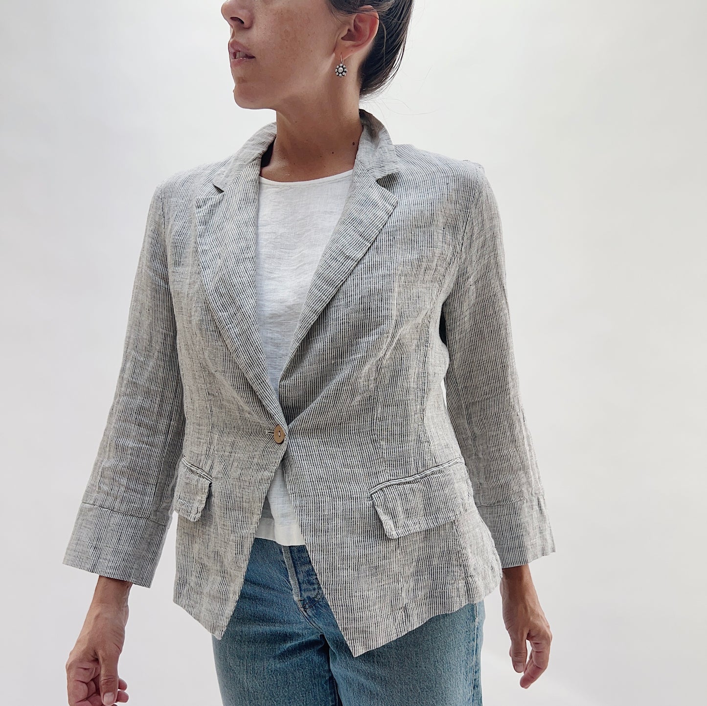Front view of the Linen Blazer in Grey Pinstripe by Yuvita, showing the notched lapel, single-button closure, and relaxed fit, styled with a white linen tee and blue jeans