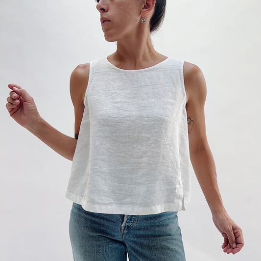 Front view of the Button Back Tank in White by Yuvita — a cropped white linen tank with a scoop neckline and side slits, styled with blue jeans on a white background