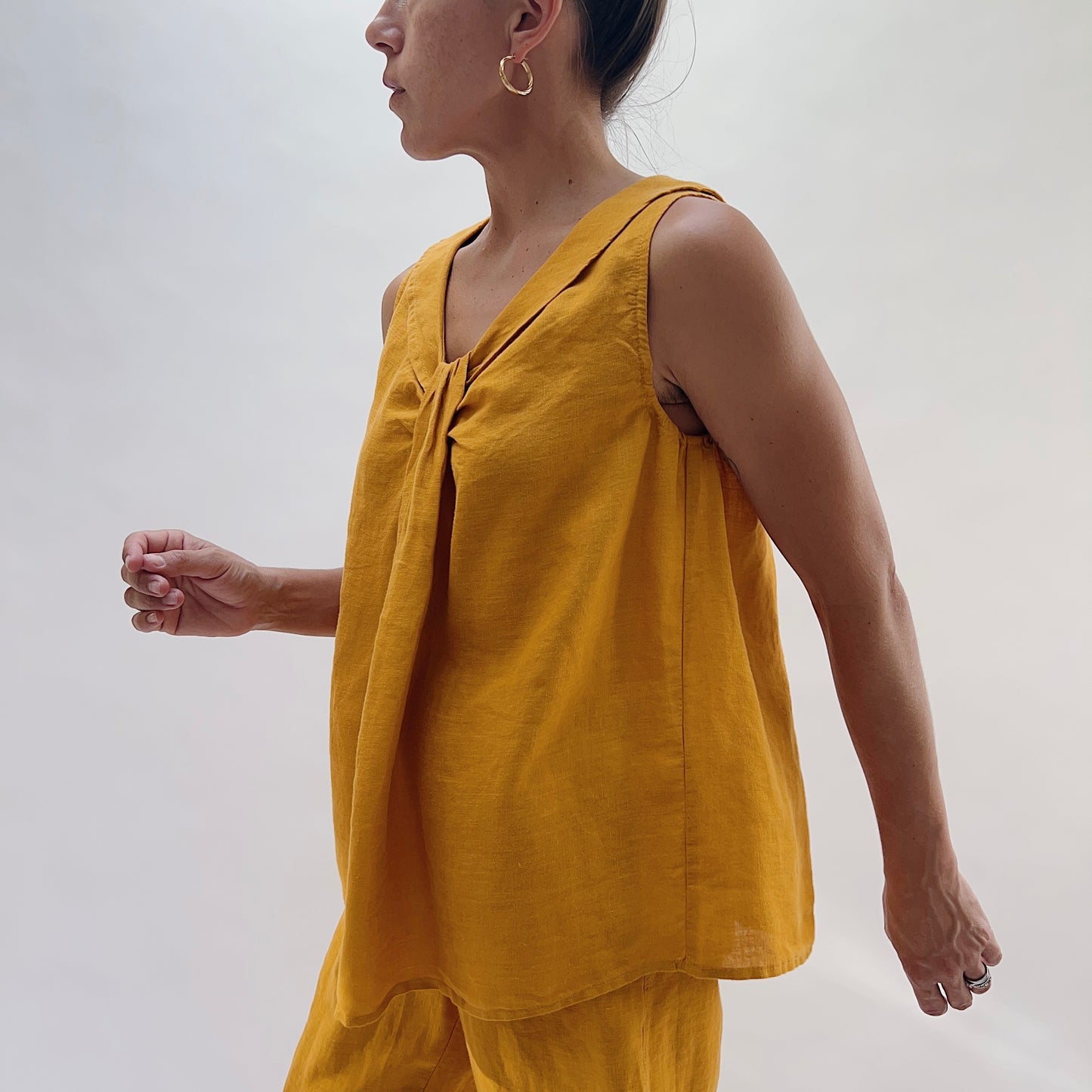 Side profile view of the Sailor Tank in Turmeric by Yuvita, showing the gathered twist neckline, sailor collar, and relaxed A-line drape in golden turmeric yellow linen, styled with matching wide-leg pants