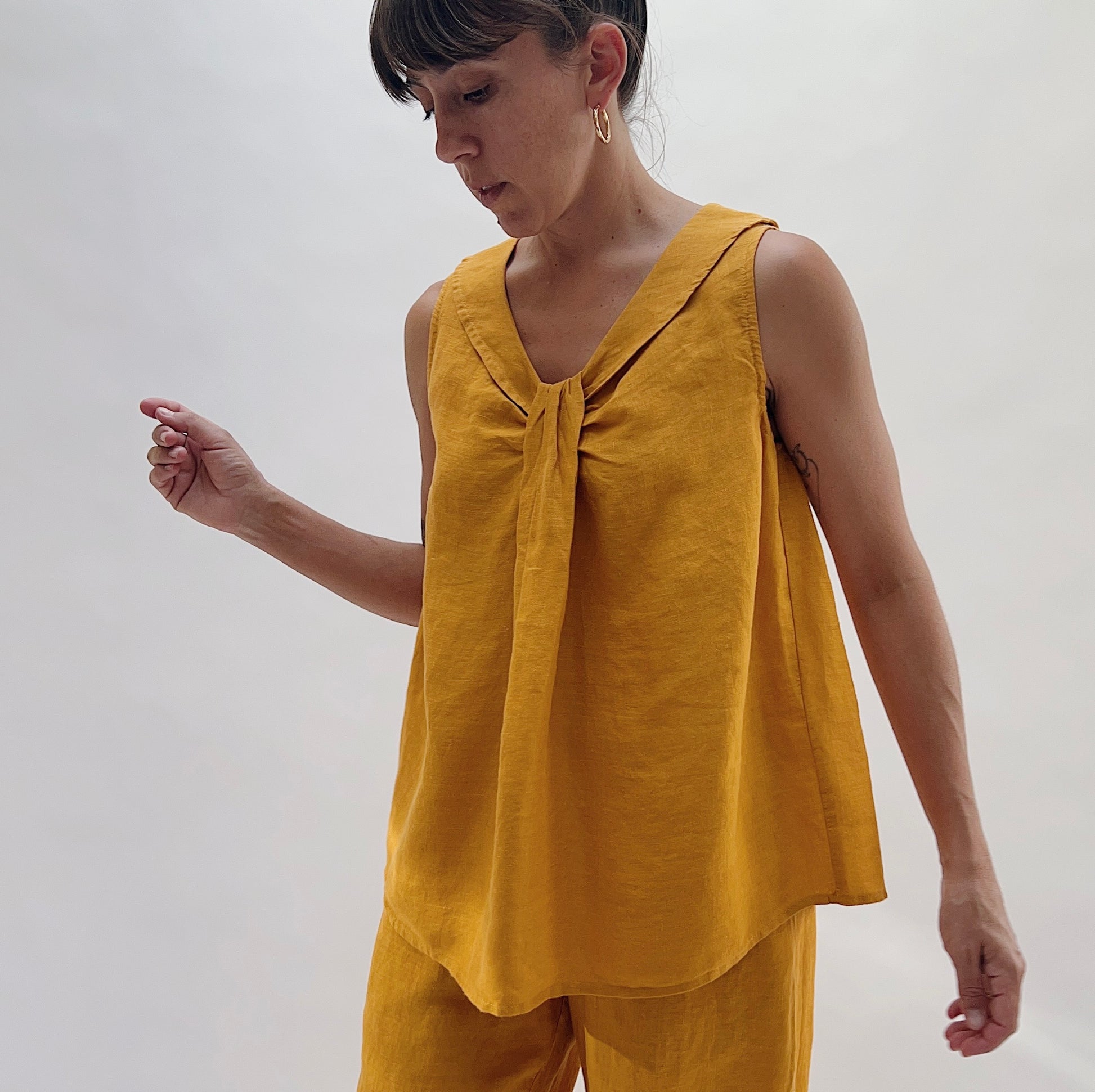 Three-quarter front view of the Sailor Tank in Turmeric by Yuvita, highlighting the gathered twist neckline and sailor collar detail in golden turmeric yellow linen, styled with matching wide-leg pants
