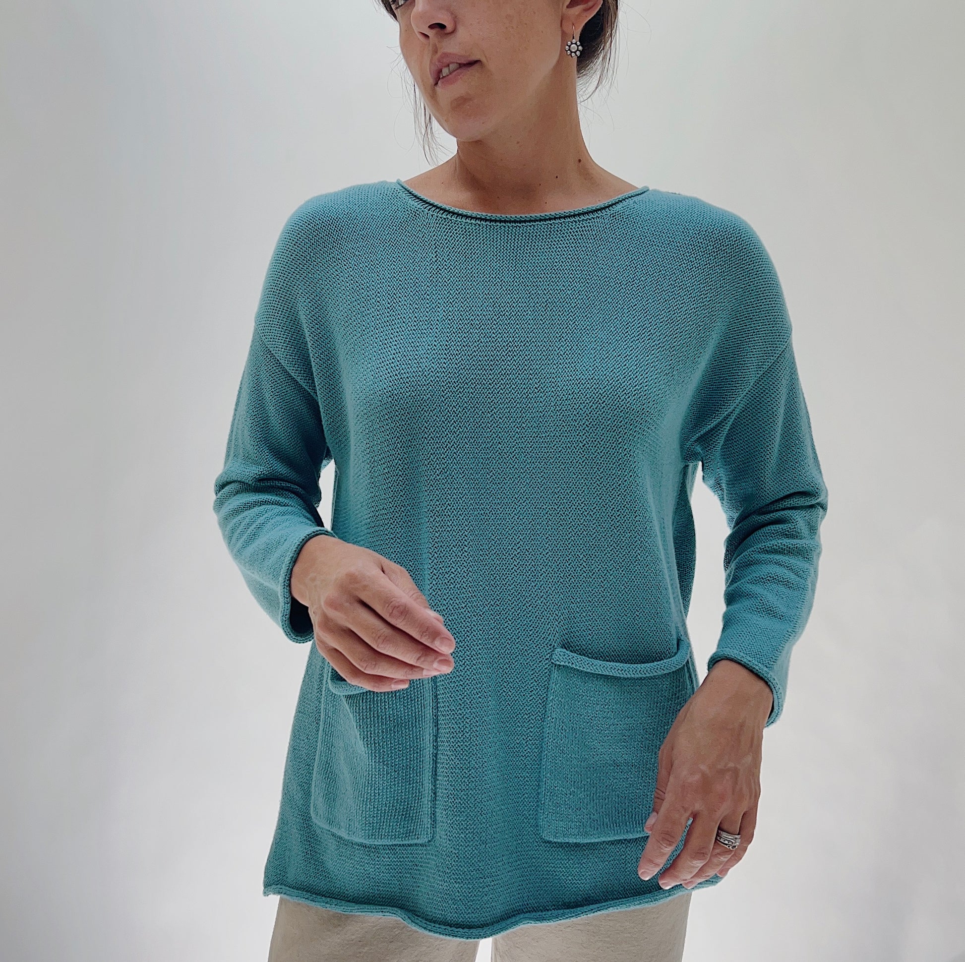 Shannon Passero Handloomed Cotton Emerson Pullover in Tide Blue — front view showing the open-stitch knit texture, boat neckline, long sleeves, and two front patch pockets, worn with cream trousers on a white background