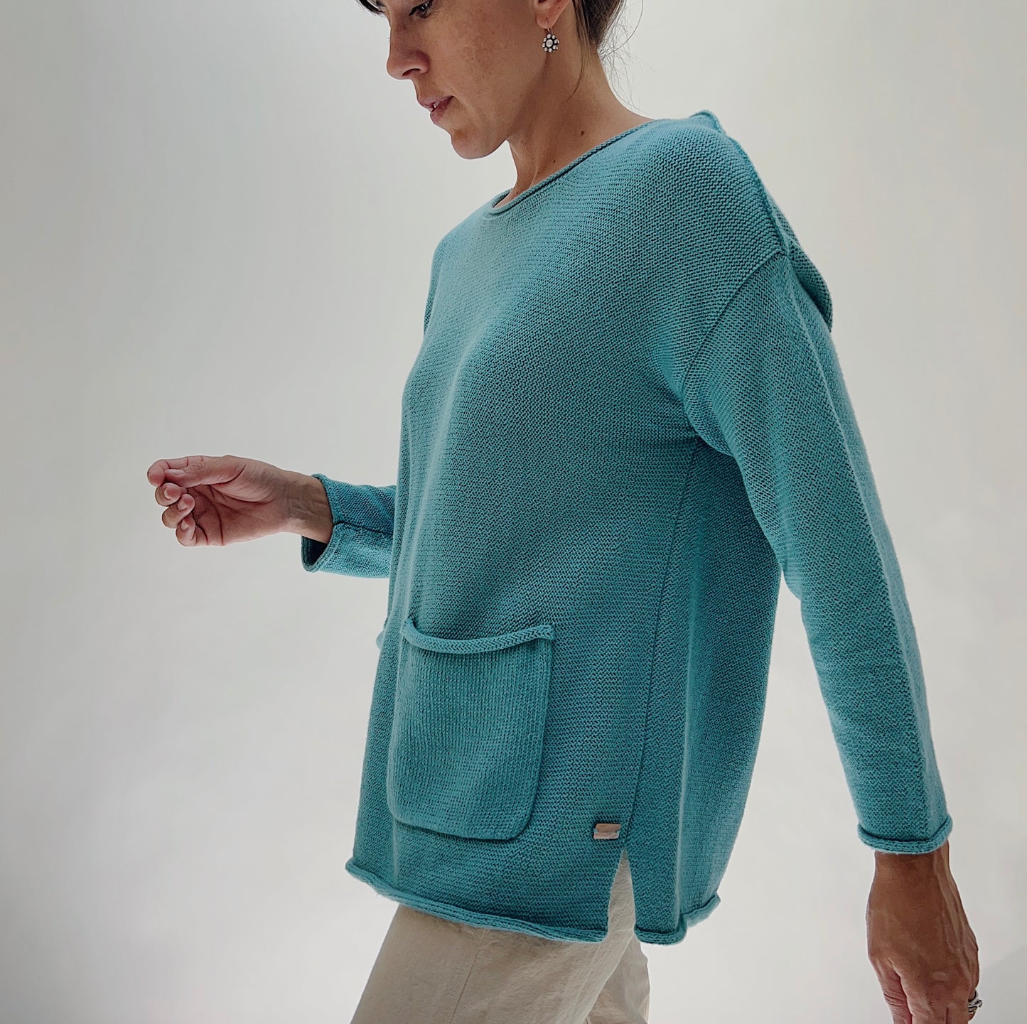Shannon Passero Handloomed Cotton Emerson Pullover in Tide Blue — side profile showing the relaxed boxy silhouette, one front patch pocket with a small woven label at the hem, and long sleeves, worn with cream trousers on a white background