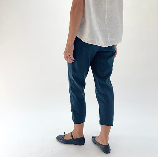 Back three-quarter view of model wearing Cut Loose Etan taper crop pant, showing tapered silhouette, side seam vent at hem, and relaxed hip fit