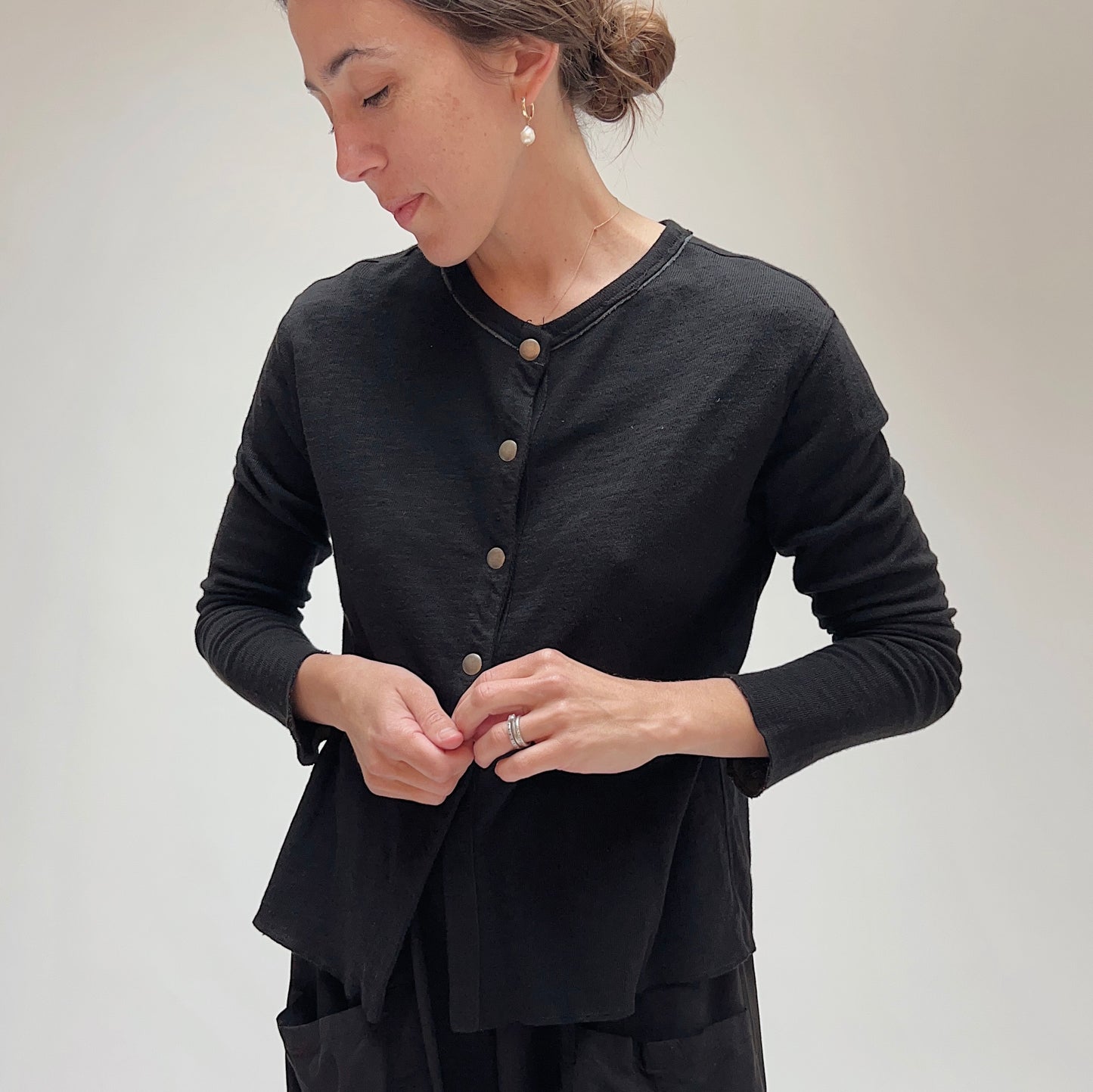 Front view of model wearing the black snap front cardigan, showing full snap placket and asymmetric hem