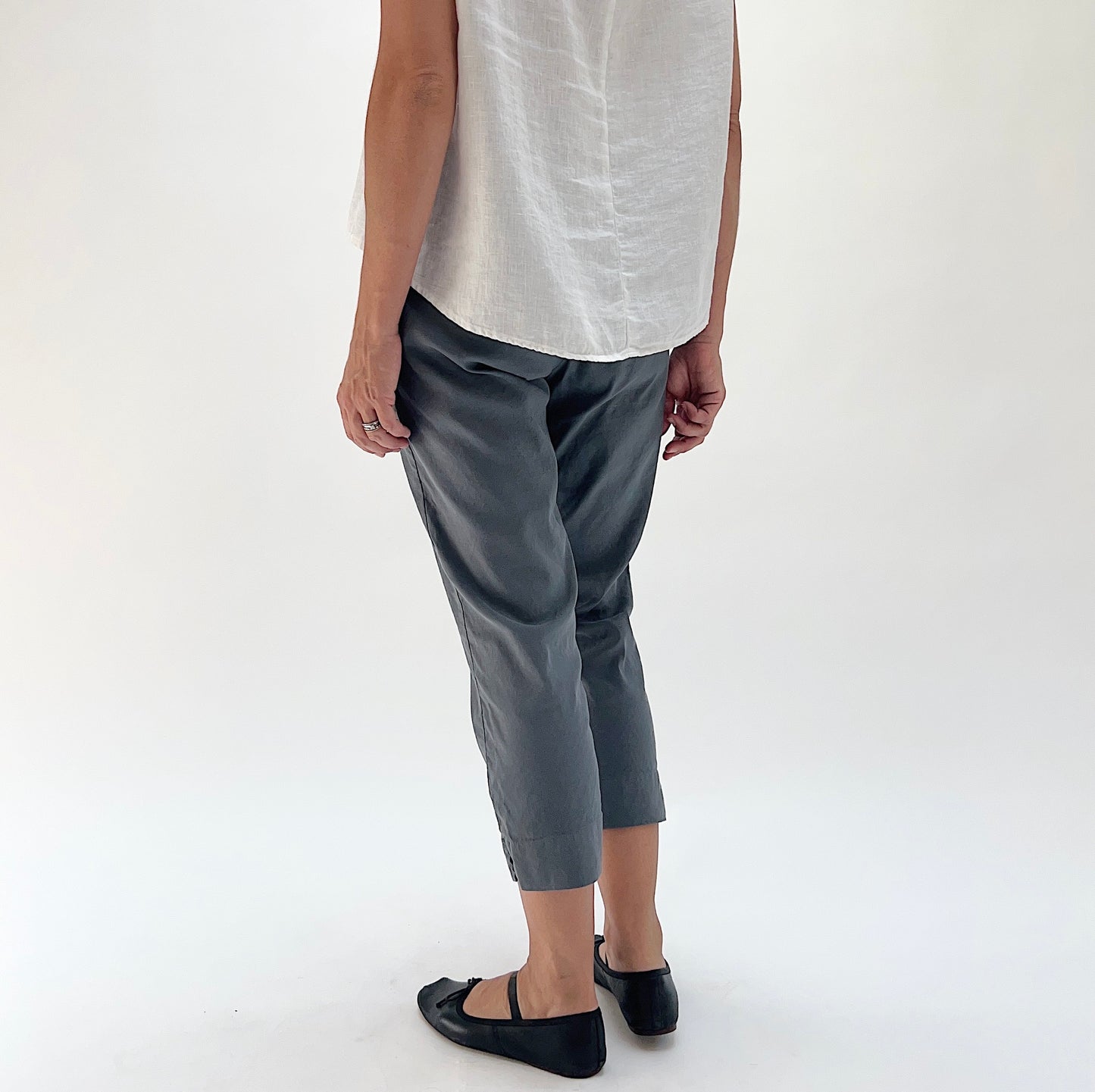 Back three-quarter view of model wearing Cut Loose iron grey taper crop pant, showing relaxed hip fit, tapered silhouette, and side seam vent at hem