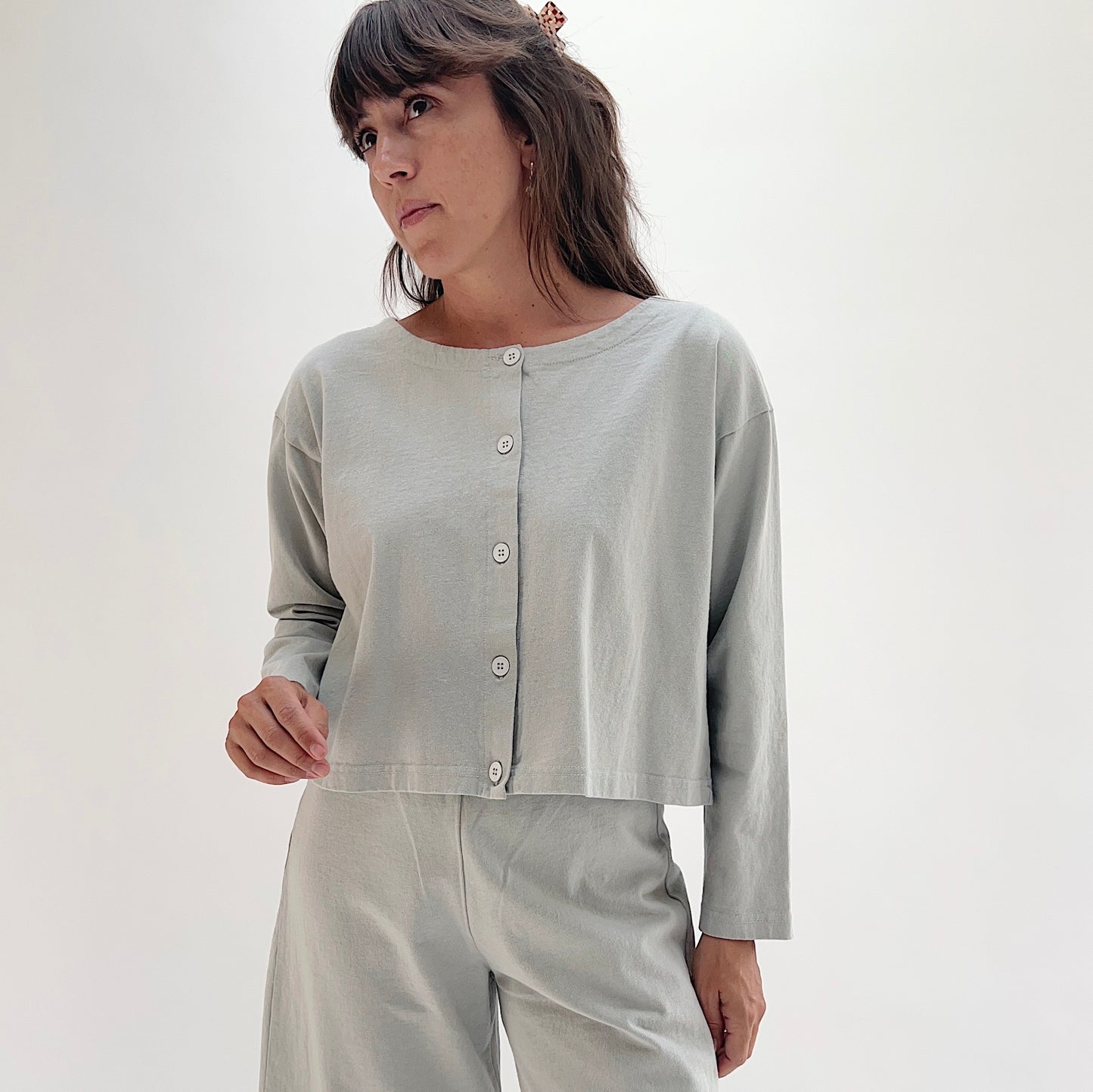 Full front view of model wearing Pacific Cotton orlaya long sleeve button front shirt, showing crew neckline, five-button center placket, long sleeves, and cropped boxy fit