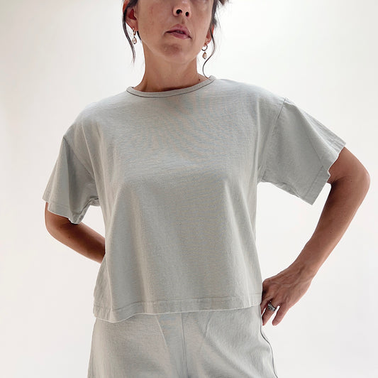 Close front view of model wearing Pacific Cotton orlaya crop crew tee, showing ribbed crew neckline, short sleeves, boxy cropped fit, and sage green color