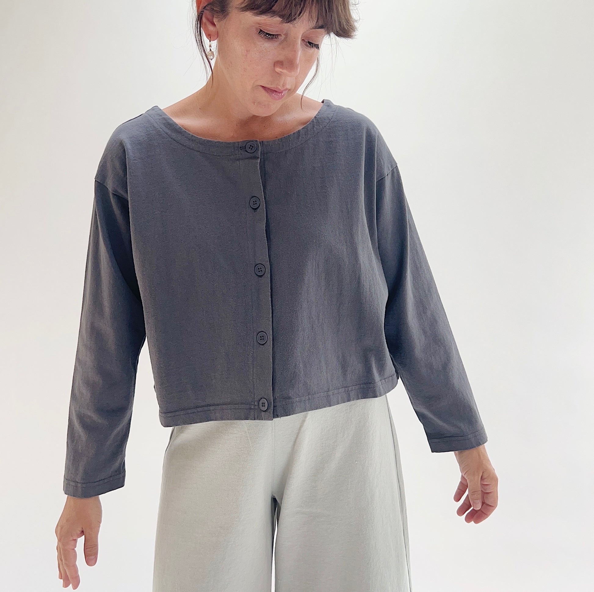 Full front view of model wearing Pacific Cotton moonlight long sleeve button front shirt, showing wide neckline, five-button center placket, long sleeves, boxy cropped silhouette, and slate blue-grey color