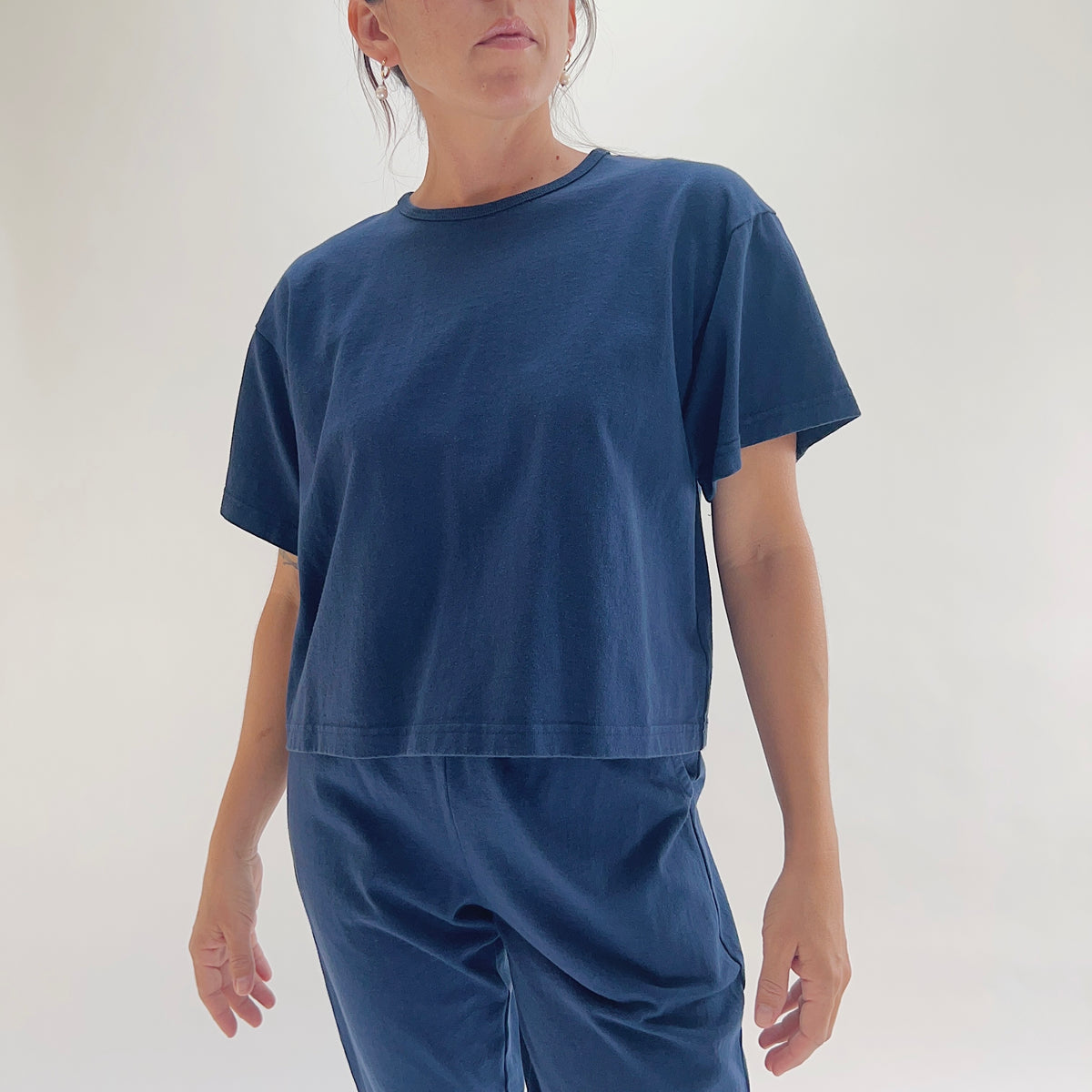 Full front view of model wearing Pacific Cotton nova crop crew tee styled with matching nova pants, showing crew neckline, short sleeves, boxy cropped fit, and deep teal color
