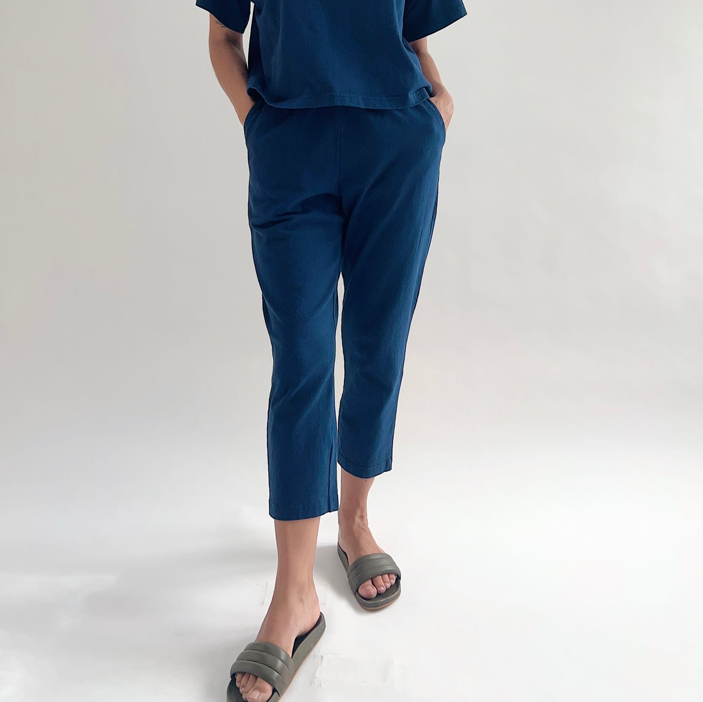 Full front view of model wearing Pacific Cotton nova sunday pant, showing elastic waistband, straight cropped leg silhouette, and deep teal color, styled with matching nova crop crew tee