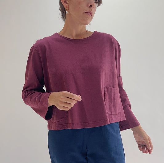 Full front view of model wearing Pacific Cotton rhone boxy shirt, showing crew neckline, two front patch pockets, long sleeves, boxy cropped fit, and berry plum color

