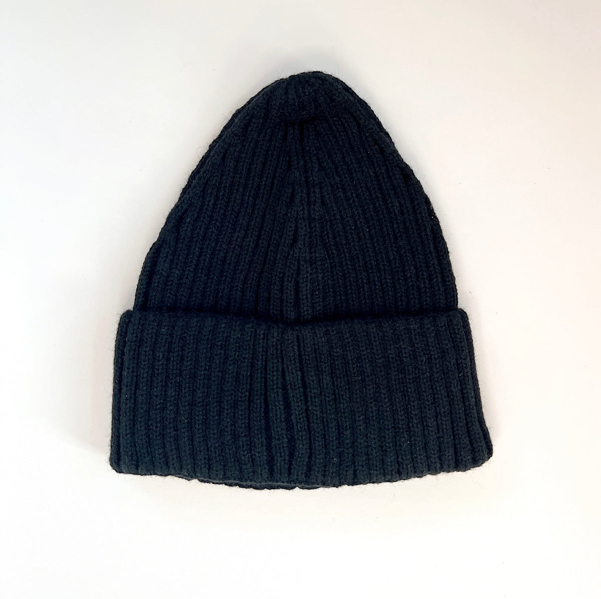 Black ribbed lambswool beanie laid flat with a wide fold-over cuff.
