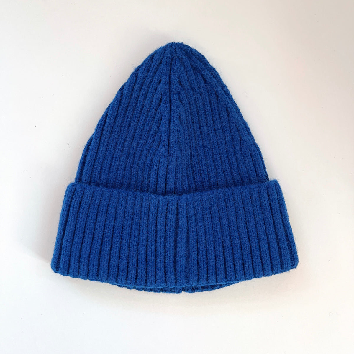 Cobalt blue ribbed lambswool beanie laid flat with a wide fold-over cuff.
