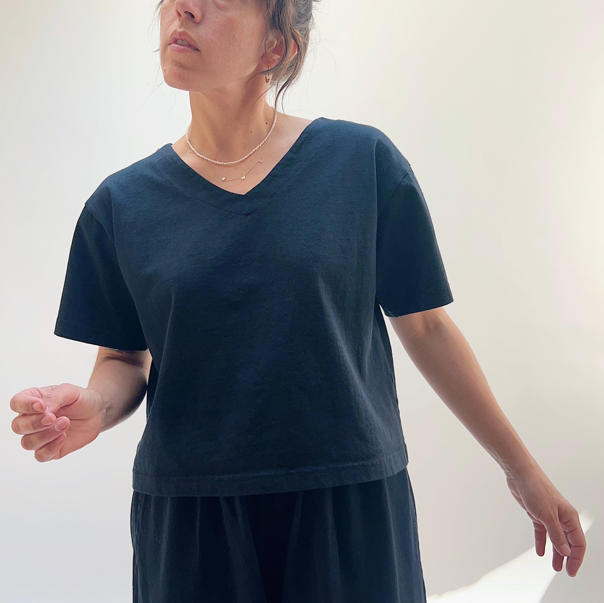 A person wearing a black crop V-neck t-shirt 