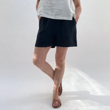 Load image into Gallery viewer, Person wearing black shorts and a white top on a white background
