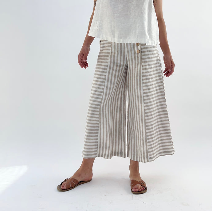 Person wearing white top and striped wide-leg pants on a white background