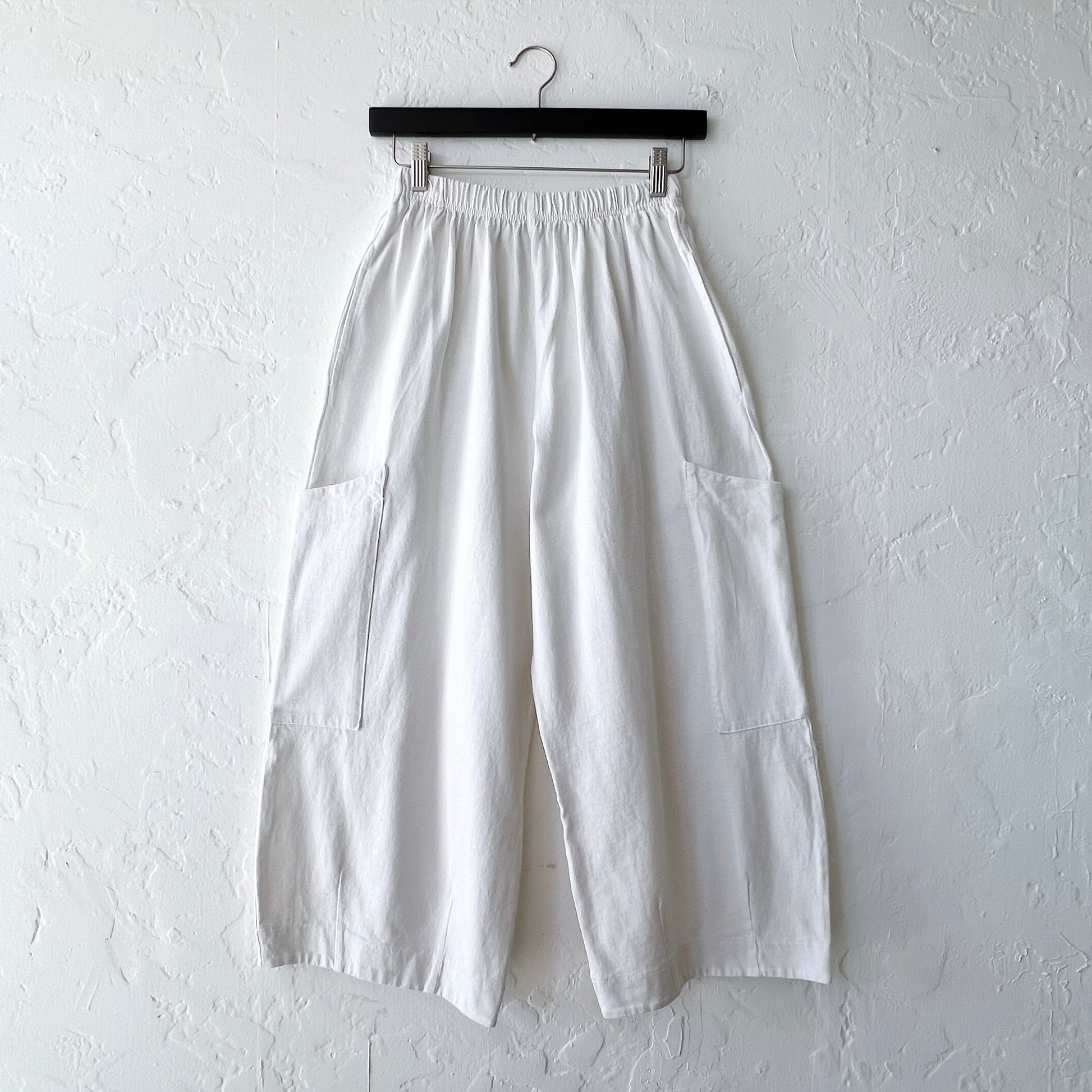 White wide-leg pants on a hanger against a white wall