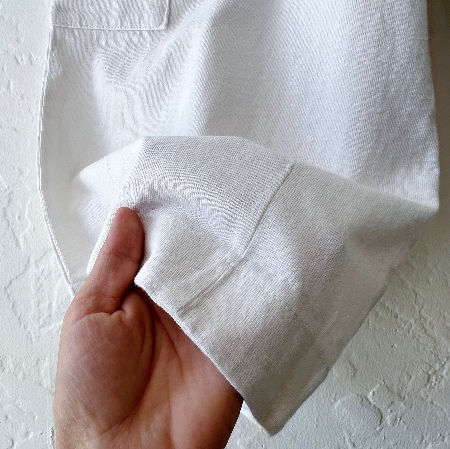 Hand holding a white fabric against a light background