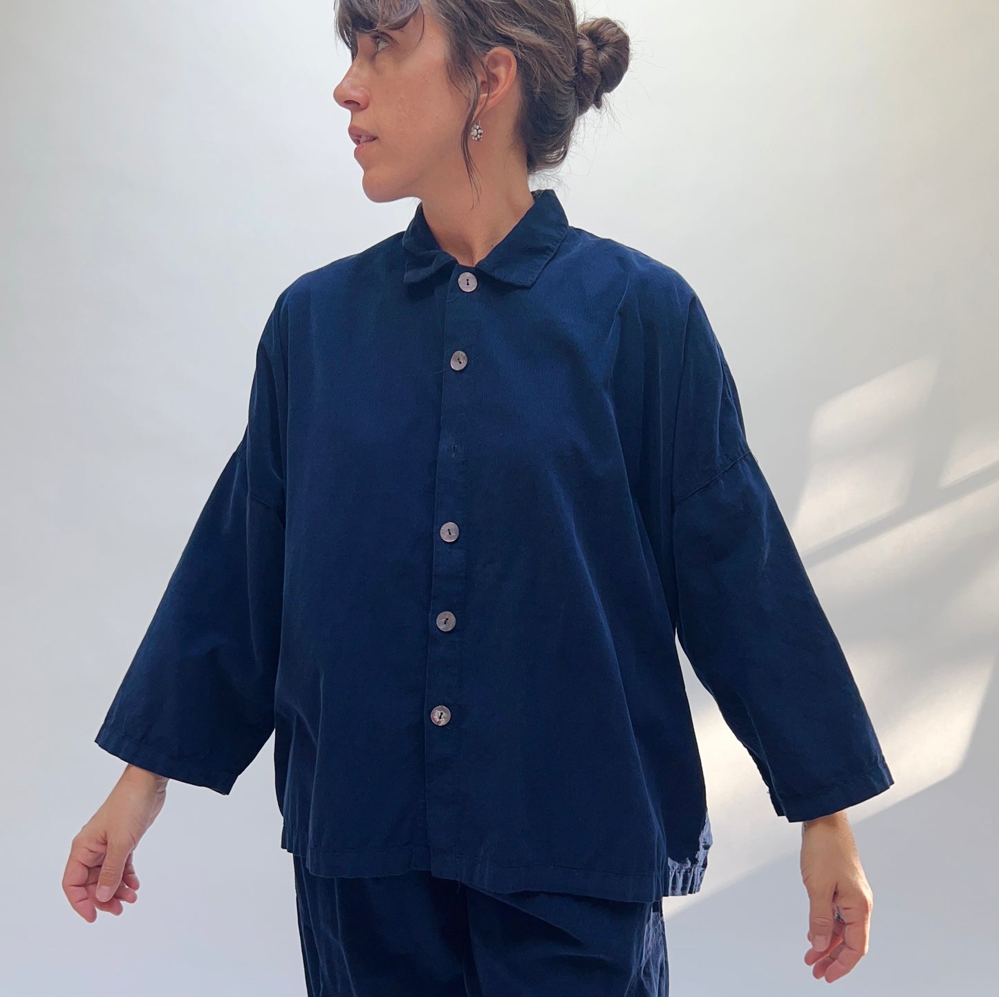 Model wearing the Eleven Stitch Corduroy Big Shirt in Indigo, side-front view, showing oversized silhouette, shell buttons, and classic collar