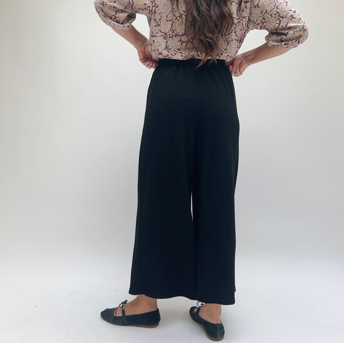 Cut Loose Marled Knit Crop Pant in Black, back view showing elastic waistband and wide-leg silhouette, styled with a floral blouse
